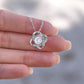 A close view of the Love knot necklace held by a woman's hand.