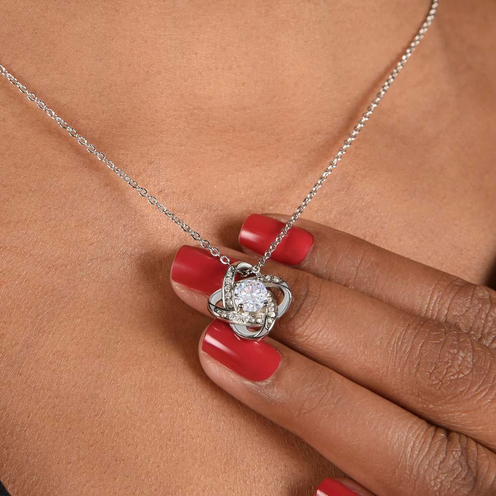 A close look at the Love Knot necklace on a woman's neck .