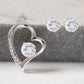 A close-up image of a heart-shaped necklace and matching earrings. 